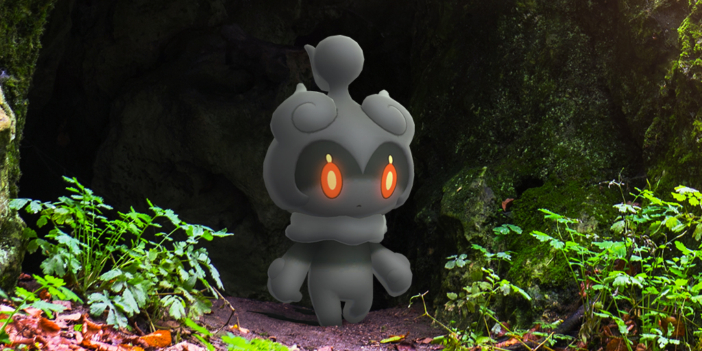Marshadow standing in front of a cave surrounded by foliage